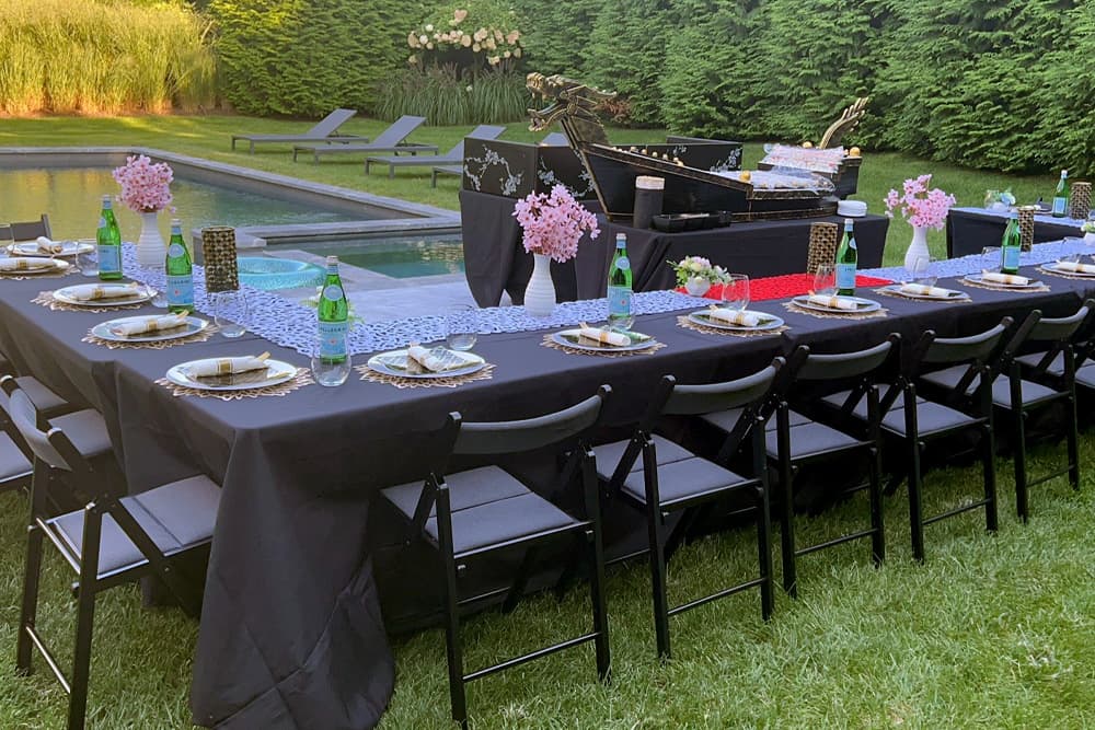 Backyard party set for outdoor hibachi and sushi, tables dressed poolside